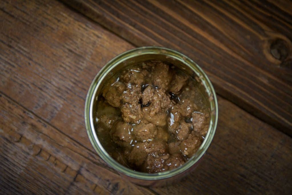 A canned cat food photographed above placed on a wooden floor