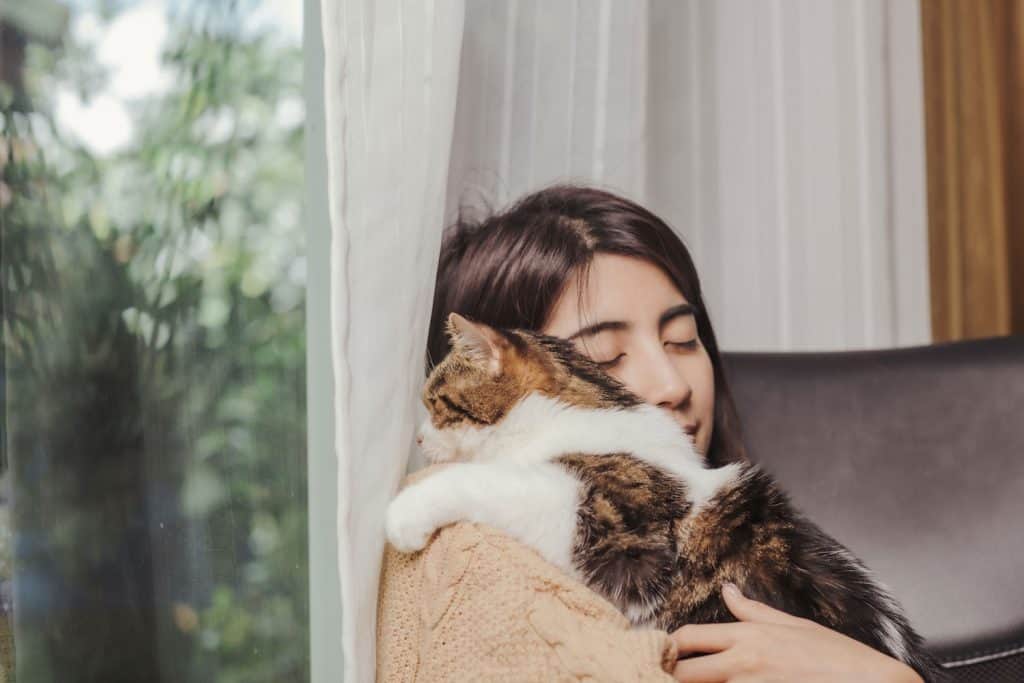 Woman hugging her cat inside her living room